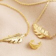 Gold Feather Bracelet, Ear Cuff, and Necklace Set on Beige Fabric
