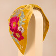 Powder Embroidered Floral Headband in Mustard on Stand Against Natural Coloured Background