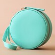 Front of Mini Round Travel Jewellery Case in Turquoise on Pink Background