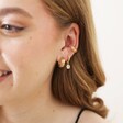 Beaded Daisy Charm Huggie Hoop Earrings in Gold Worn by Model With Other Gold Earrings