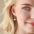 Close Up of Model Wearing Daisy, Pearl and Feather Hoop Earrings in Gold Looking to Side