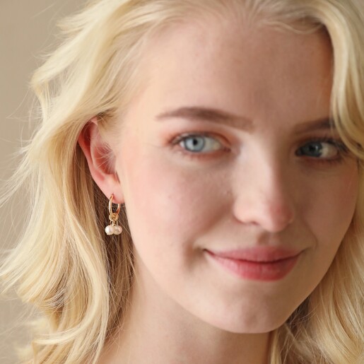 Model Wearing Daisy, Pearl and Feather Hoop Earrings in Gold Looking to the Side