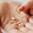 Model Holding Daisy, Pearl and Feather Hoop Earrings in Gold in Palm of Hand