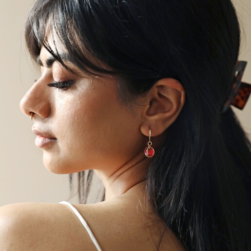 Model Wearing Pressed Birth Flower Huggie Hoop Earrings in Gold with Neutral Background