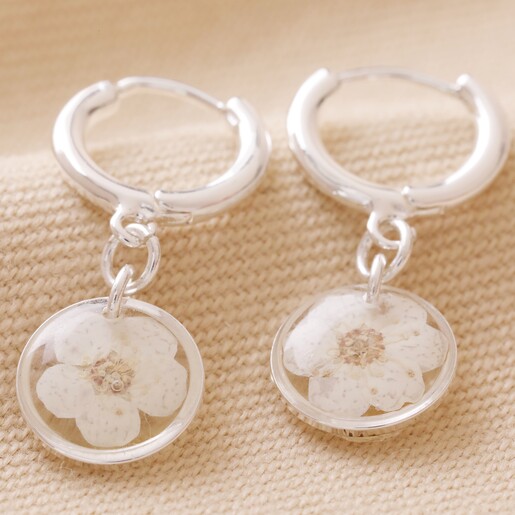 April Charm of Pressed Birth Flower Huggie Hoop Earrings in Silver on Neutral Coloured Fabric