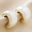Small Pearlescent Hoop Earrings in Gold on Top of Folded Up Fabric