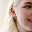 Close Up of Model Wearing Starry Green Enamel Hoop Earrings with Cream Background