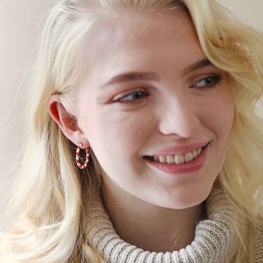 Model wearing red and white twisted enamel hoops in gold 