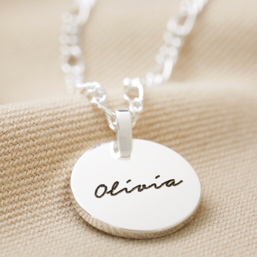 Close Up of Silver Disc Pendant With Blackened Engraving and LA Pen Script Font