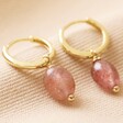 Strawberry Quartz Stone Huggie Hoop Earrings in Gold on Beige Fabric