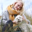 Model Wearing Mustard Harlequin Winter Scarf Sitting with Small White Dog