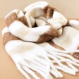 Neutral Striped Winter Scarf Laid Out on Peach Background