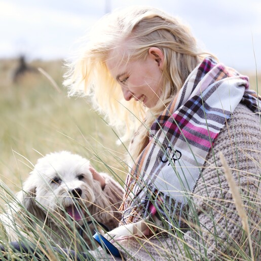 Model Wearing Personalised Colourful Tartan Winter Scarf Sitting Next to Small White Dog