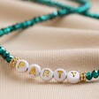 Zoomed in on Party Beads on Teal Beaded Party Necklace in Gold Laid on Beige Fabric