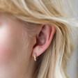 Close Up of Blonde Model Wearing Baguette Crystal Huggie Hoop Earrings in Gold