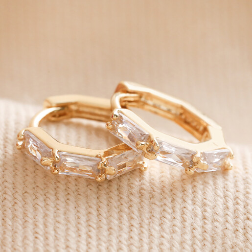 Baguette Crystal Huggie Hoop Earrings in Gold on Beige Fabric