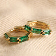 Green Baguette Crystal Huggie Hoop Earrings in Gold on Natural Coloured Fabric