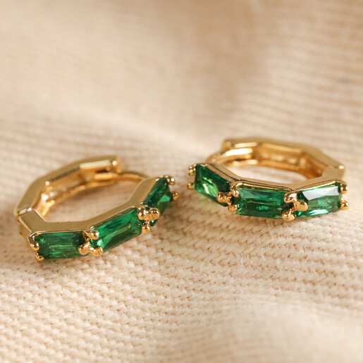 Green Baguette Crystal Huggie Hoop Earrings in Gold Green Baguette Crystal Huggie Hoop Earrings in Gold on Neutral Coloured Fabric