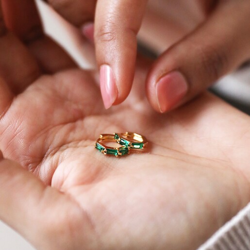 Earrings in Hand Model Holding Green Baguette Crystal Huggie Hoop Earrings in Gold in Palm of Hand