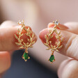 Model Holding Green Stone and Crystal Fern Drop Earrings in Gold