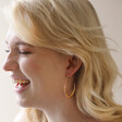 Model Laughing Wearing Hammered Teardrop Hoop Earrings in Gold