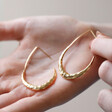 Model Holding Hammered Teardrop Hoop Earrings in Gold in Hand