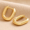 Oval Huggie Hoop Earrings in Gold on Neutral Fabric
