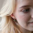 Close Up of Blonde Model Wearing Small Gold Flower and Green Crystal Drop Earrings