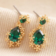 Small Gold Flower and Green Crystal Drop Earrings on Beige Fabric