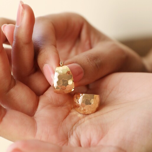 Model Holding Wide Hammered Hoop Earrings in Gold in Palm of Hand