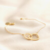 Organic Interlocking Hoops Bracelet in Gold laid on top of beige coloured fabric