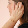 Close up of Organic Interlocking Hoops Bracelet in Gold on model with hand in hair