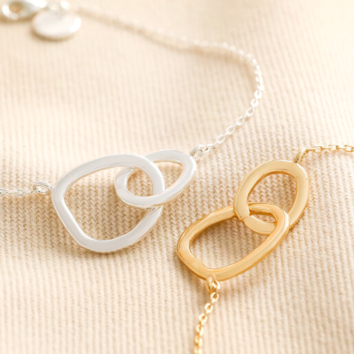 Organic Interlocking Hoops Bracelets in Silver and Gold on Beige Fabric