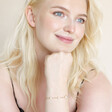 Smiling Model Wearing Pearl and Crystal Moon and Stars Bracelet in Gold With Chin Resting on Hand