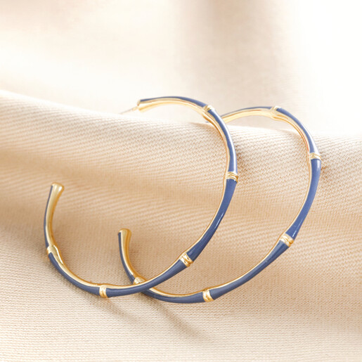 Blue Enamel Bamboo Style Hoop Earrings in Gold on top of beige coloured fabric