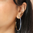 Close up of Blue Enamel Bamboo Style Hoop Earrings in Gold on dark-haired model