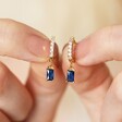 Model Holding Blue Stone and Crystal Charm Huggie Hoop Earrings in Gold