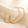 Brown Enamel Bamboo Style Hoop Earrings in Gold on top of beige coloured fabric