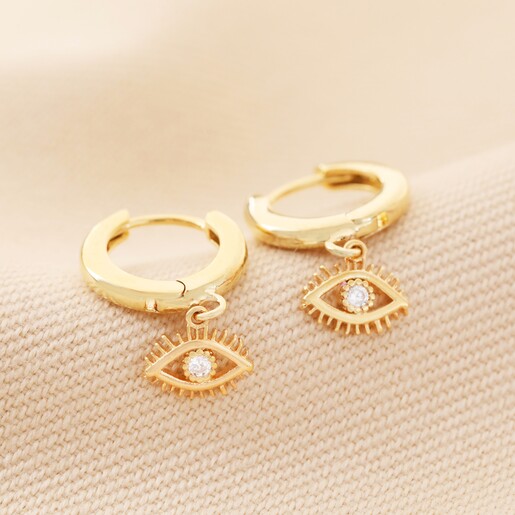 Crystal Evil Eye Huggie Hoop Earrings in Gold on Beige Fabric