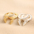 Crystal Spike Huggie Hoop Earrings in Silver with Gold Pair on Beige Fabric