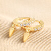 Crystal Spike Huggie Hoop Earrings in Gold on Beige Fabric 