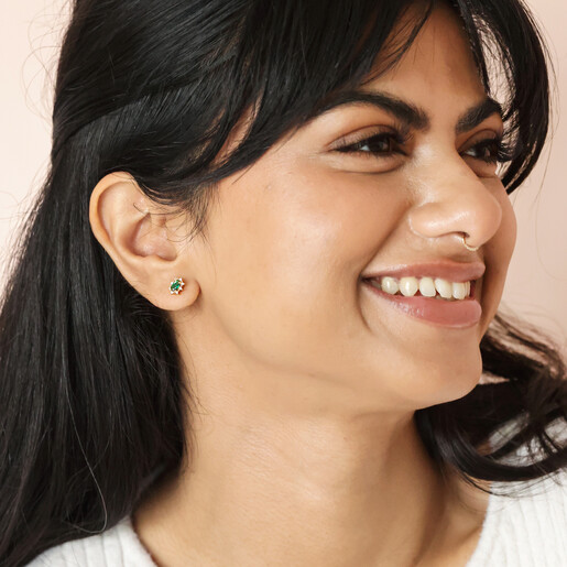Model smiling wearing Green Crystal Stud Earrings in Gold