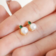 Green Crystal and Pearl Stud Earrings in Gold Held in Model's Hand