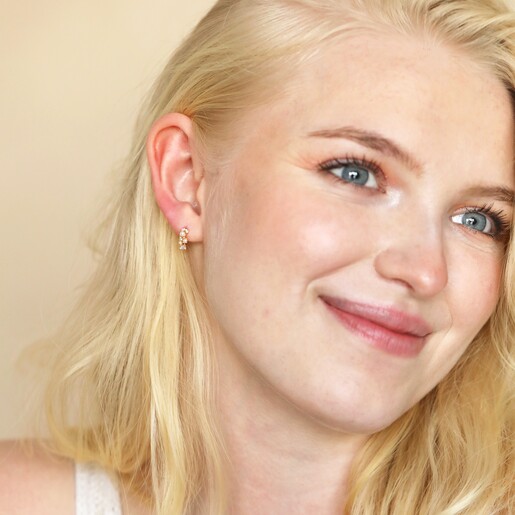 Blonde model wearing the Irregular Pearl and Crystal Huggie Hoop Earrings in Gold