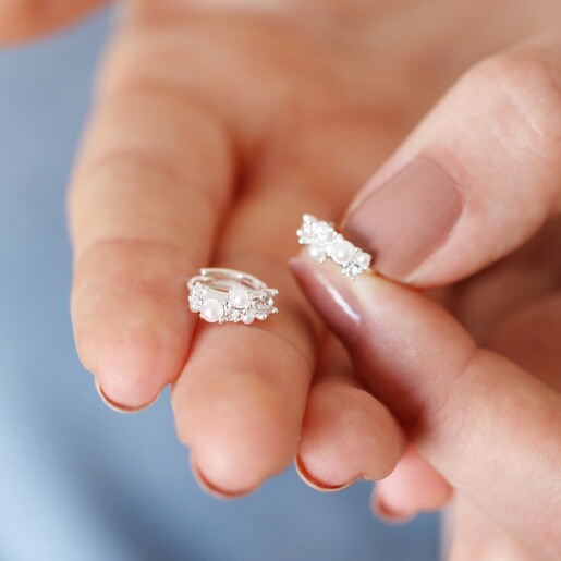 Model holding the Irregular Pearl and Crystal Huggie Hoop Earrings in Silver