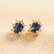 Blue Crystal Stud Earrings in Gold on Beige Fabric