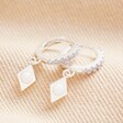 Opal Diamond Huggie Hoop Earrings in Silver laid on top of beige coloured fabric