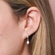 Close up of Opal Diamond Huggie Hoop Earrings in Silver on model