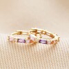 Pastel Baguette Crystal Huggie Hoop Earrings in Gold laid on top of neutral fabric