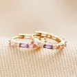 Pastel Baguette Crystal Huggie Hoop Earrings in Gold laid on top of neutral fabric